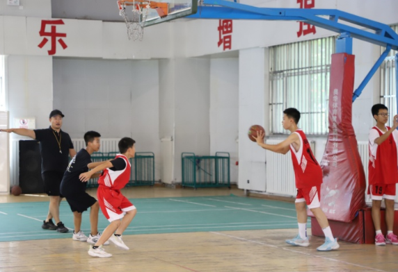 与学校教育深度交融在篮球教练正带着孩子们练习上篮与传球